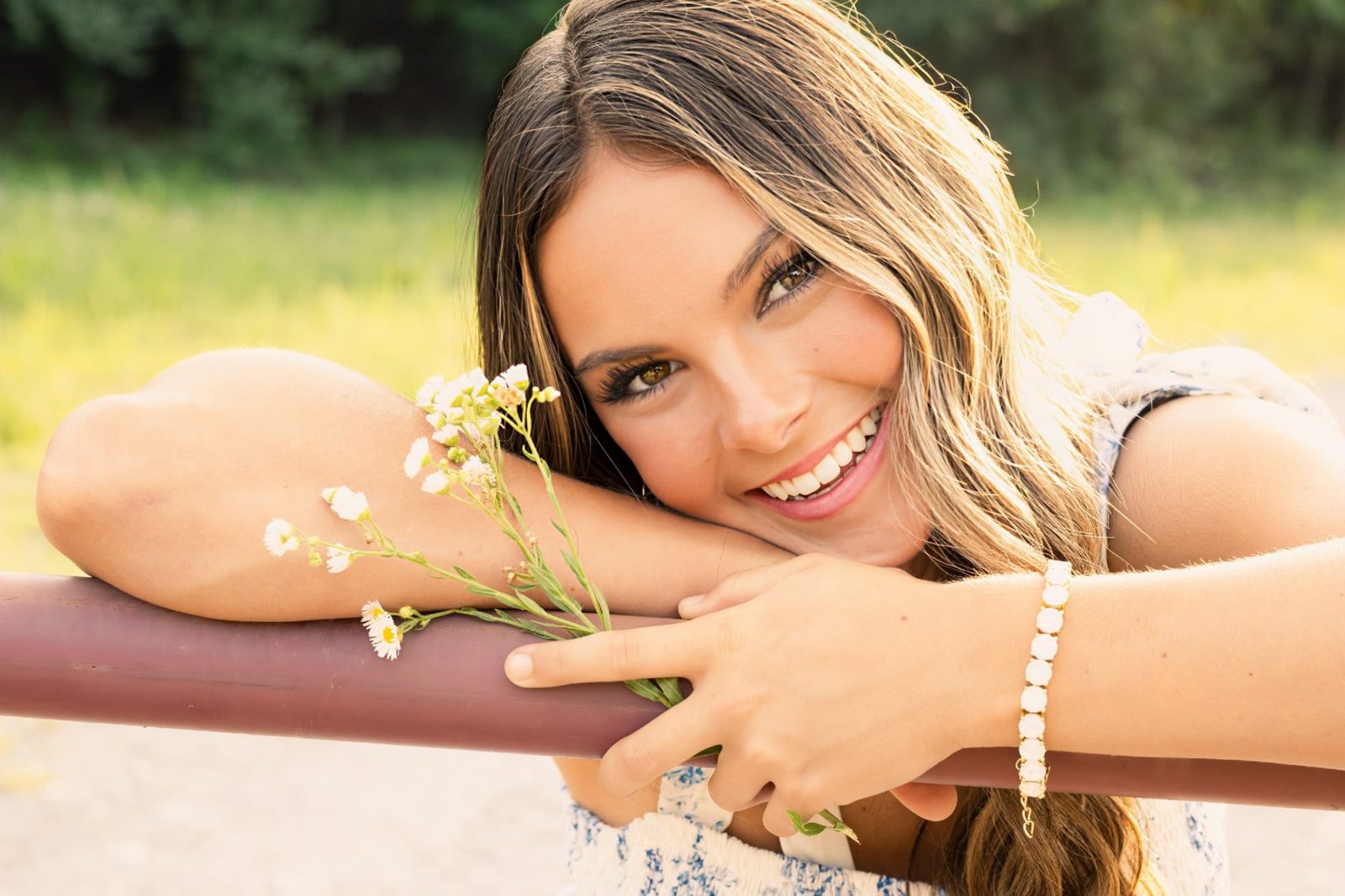 Senior leaning on a fence holding wildflowers