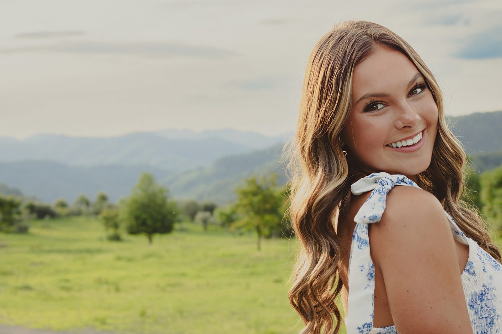 Senior leaning on a rustic rail in green hills