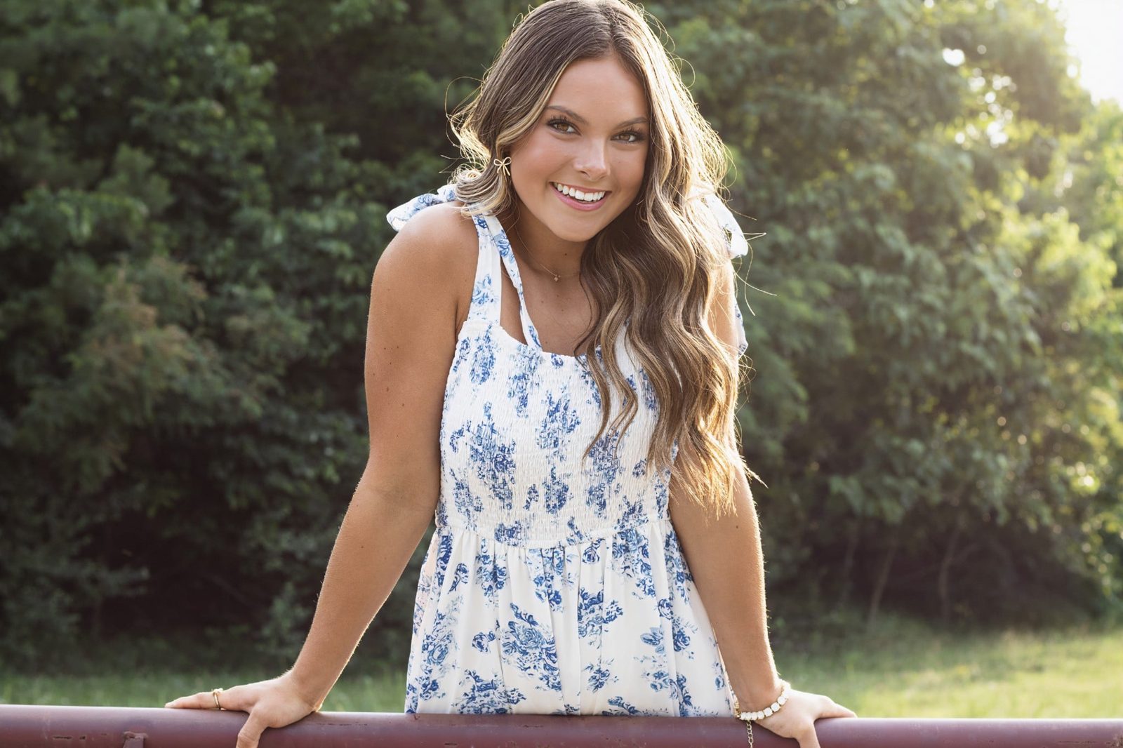 Senior in a blue floral dress by a fence