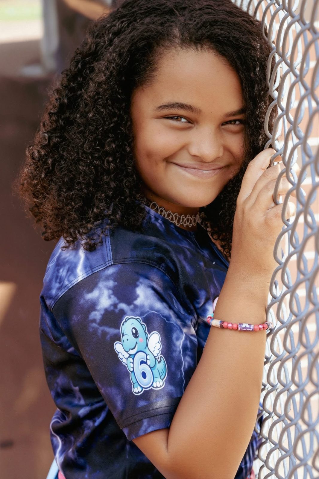 Young athlete in her jersey at the ball field fence